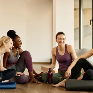 Four women chatting in a Yoga studio.