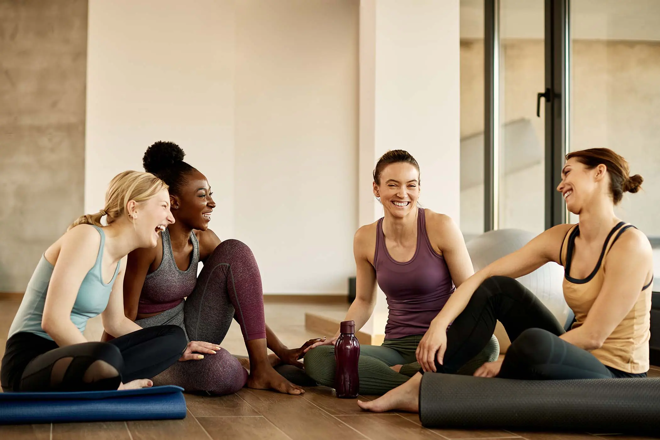 Four women chatting in a Yoga studio.